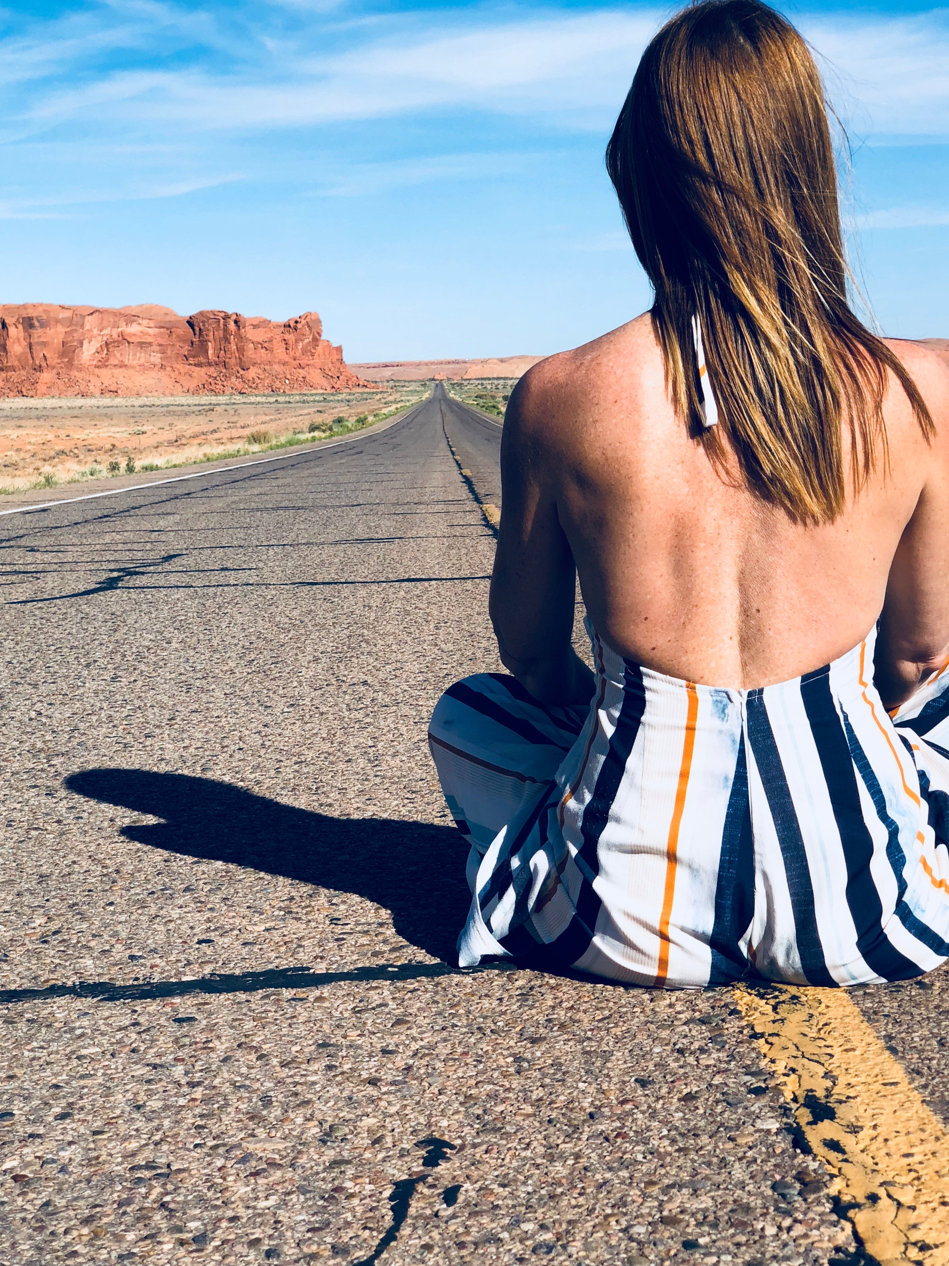 a-woman-sat-in-the-middle-of-a-highway-through-the-desert